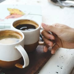 Two stoneware mugs of Americano on a wooden table