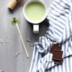 A matcha latte beside a bamboo whisk